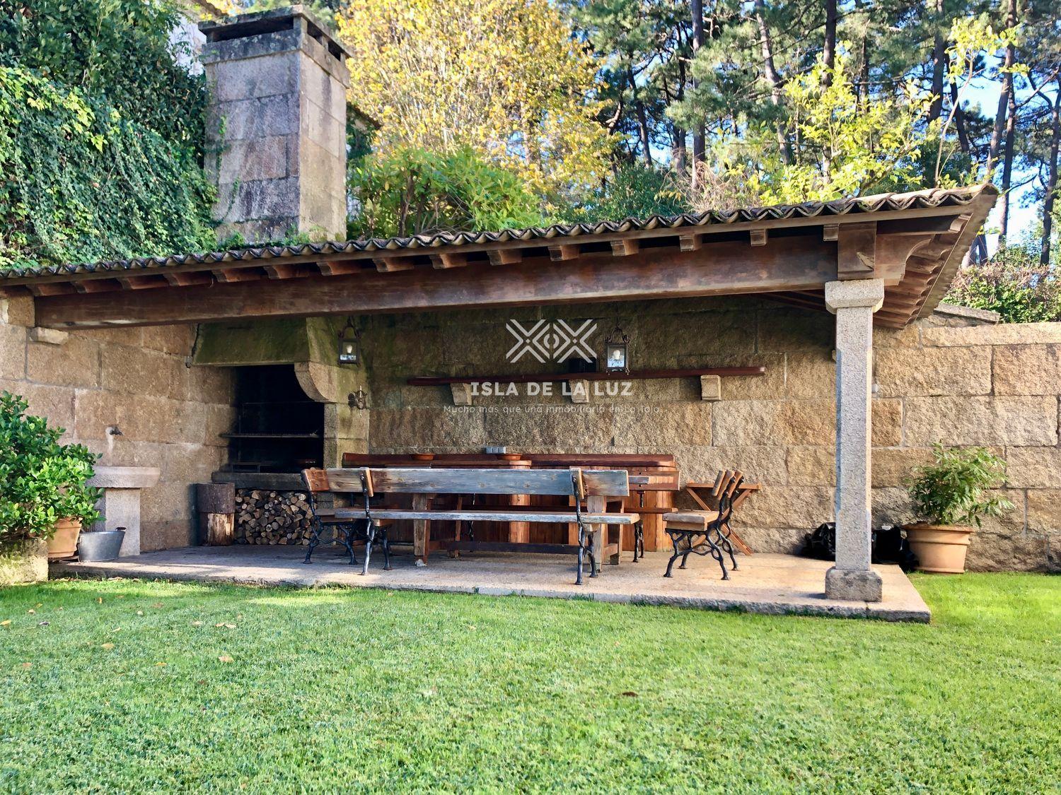 Zona de alpendre con barbacoa y mesa para comer