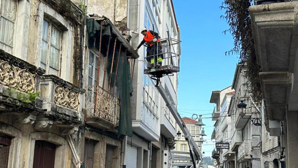 Operarios retiran elementos que suponían un peligro en un edificio en ruinas de la calle Travesa.