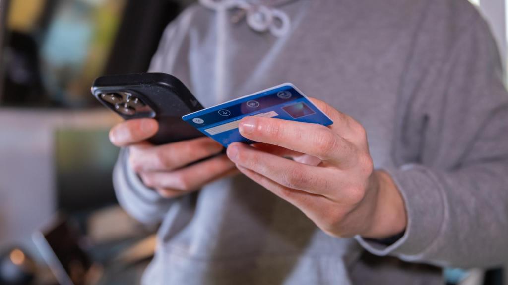 Imagen de una persona sujetando un teléfono móvil y una tarjeta de crédito.