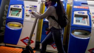Una chica con un patinete en el Metro de Madrid.