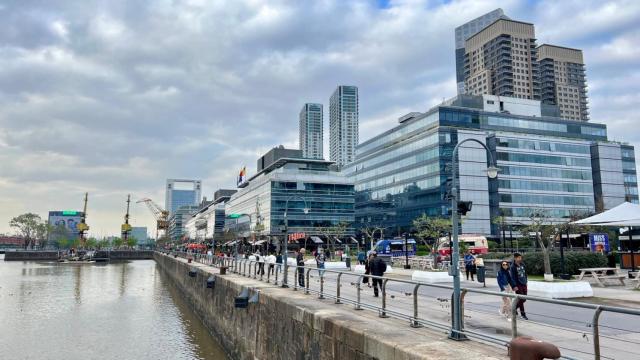 Varias personas pasean a orillas de uno de los muelles del Río de la Plata en Puerto Madero, Buenos Aires.