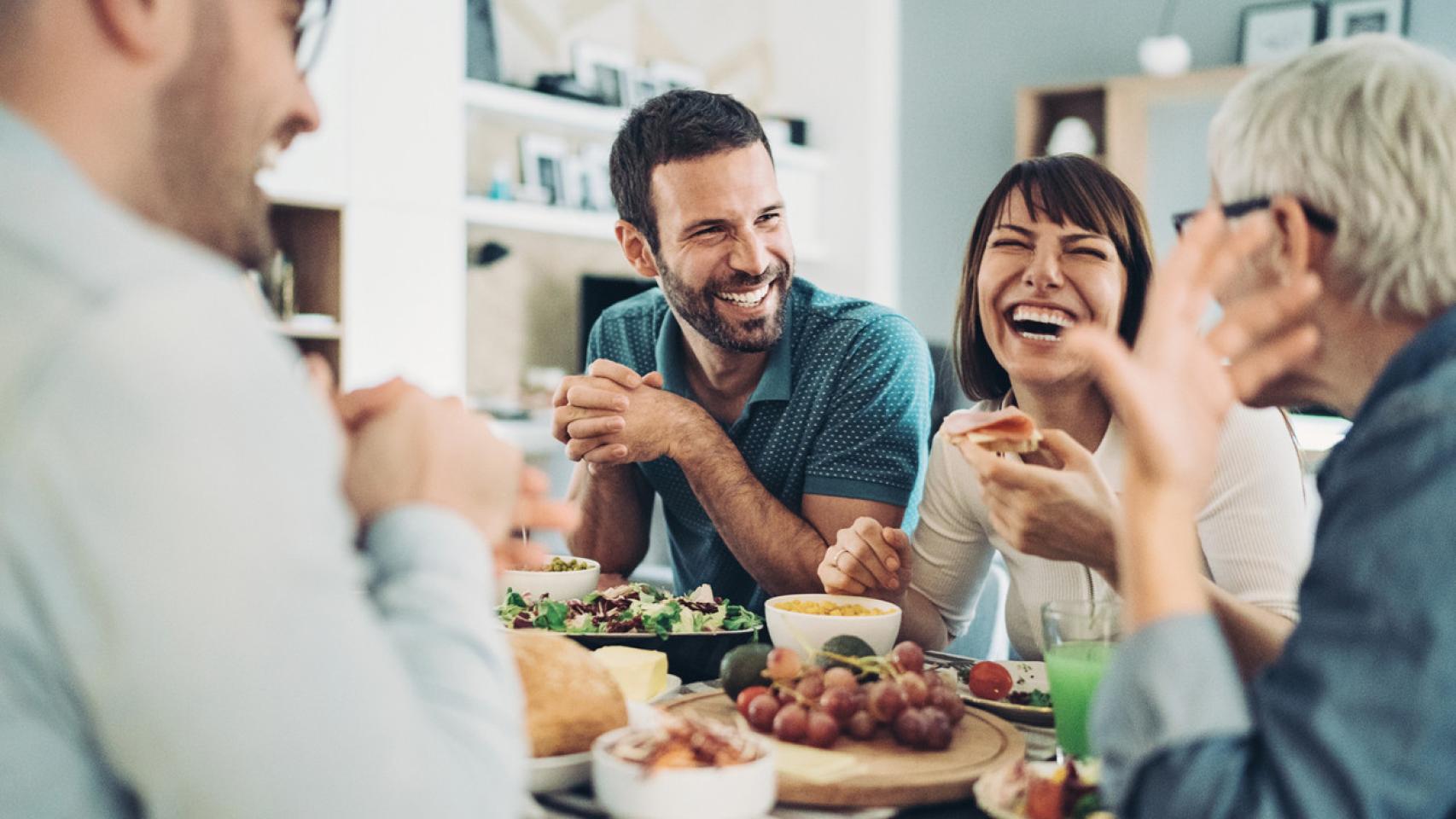Imagen de un grupo de adultos comiendo y riendo