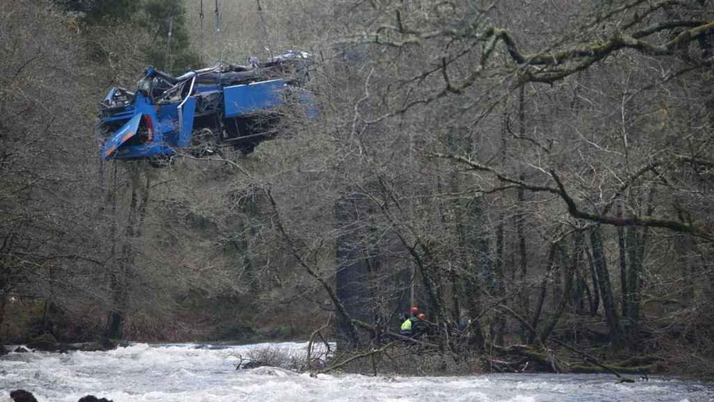 Una grúa participa en la labor de izado del autobús accidentado para sacarlo del cauce del río Lérez.