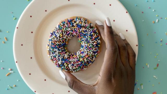 Una mujer, sujetando un donut.