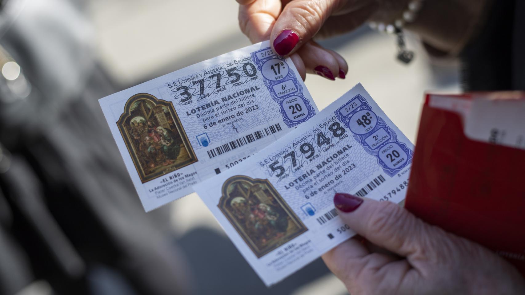 Una mujer sujetando dos décimos de la Lotería del Niño.