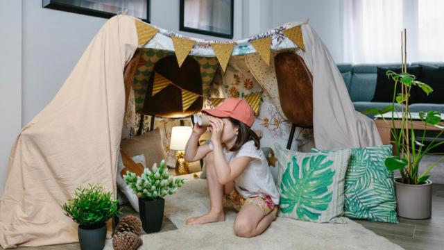 Niña jugando con un 'fuerte' hecho de sábanas.