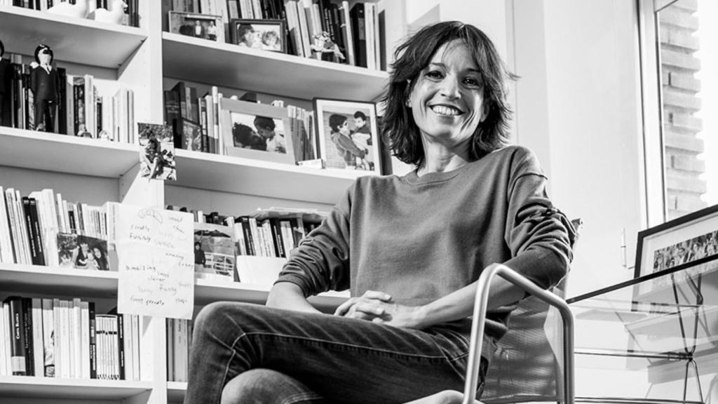 La escritora posa con su biblioteca de fondo.