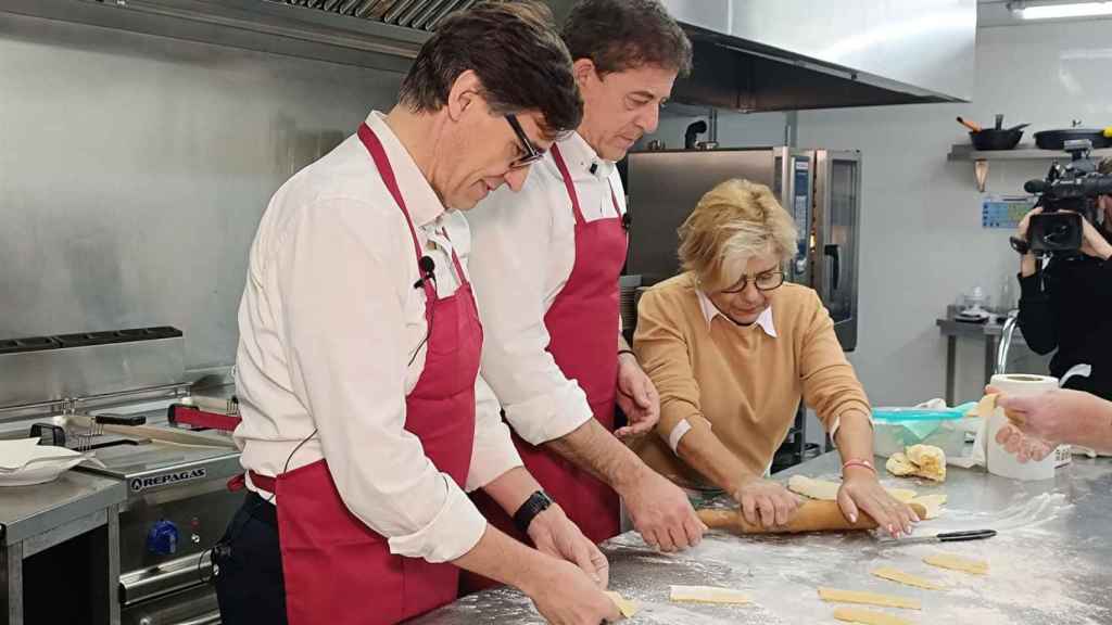 El secretario general del PSOE catalán, Salvador Illa, y el candidato socialista a la Presidencia de la Xunta, José Ramón Gómez Besteiro, aprenden a amasar orejas junto a Malena Iglesias.