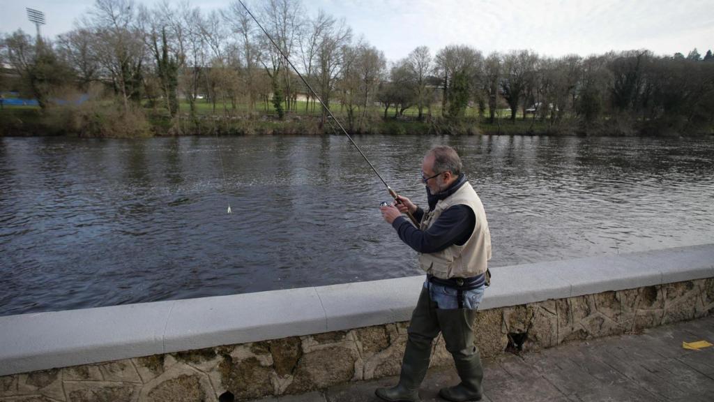 Un pescador lanza la caña en el río.