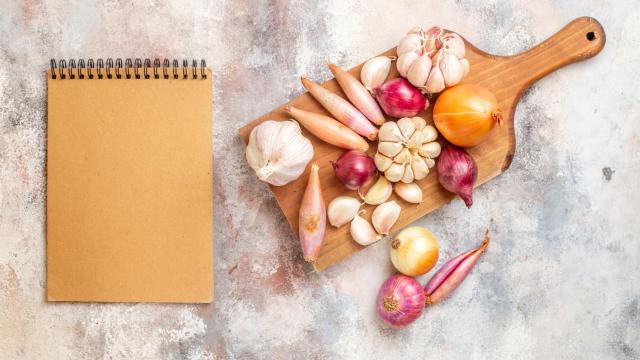 Conjunto de cebollas y ajos con una libreta.