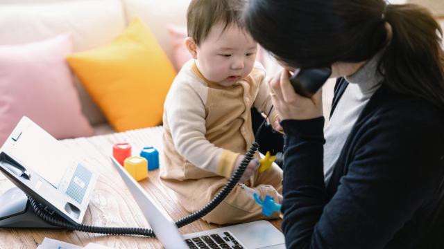 Imagen de archivo de una madre que cuida de su bebé mientras trabaja.