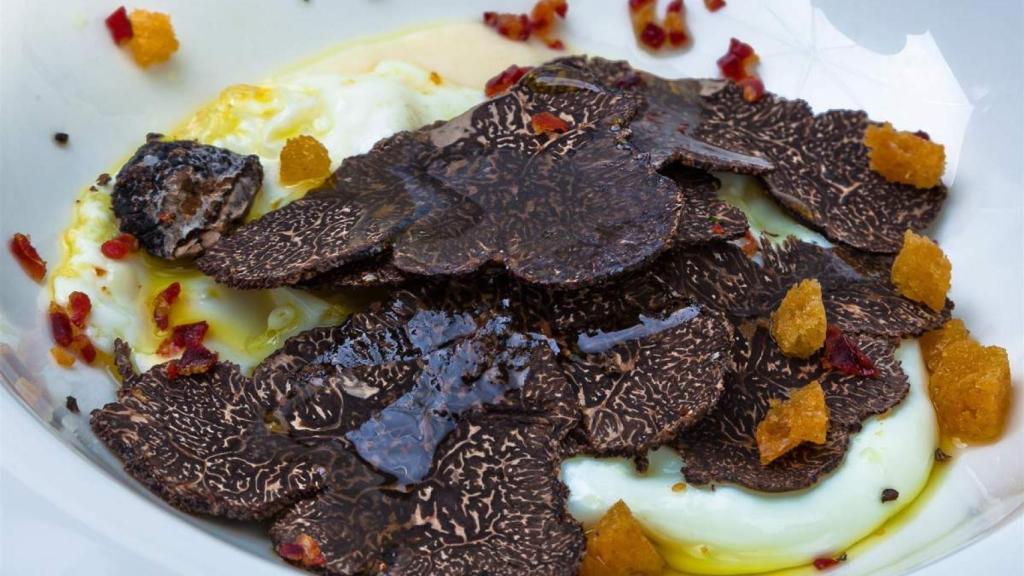 Un plato de huevos acompañados con trufa negra