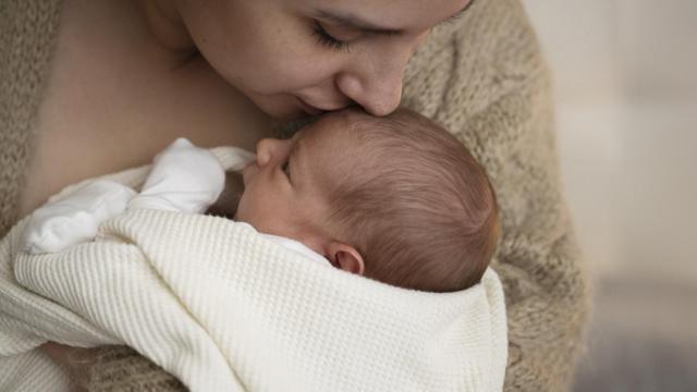Madre besando en la frente a su hijo.