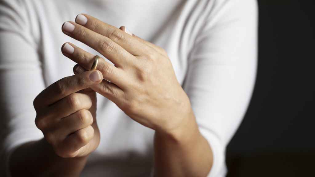 Mujer quitándose un anillo de casada.