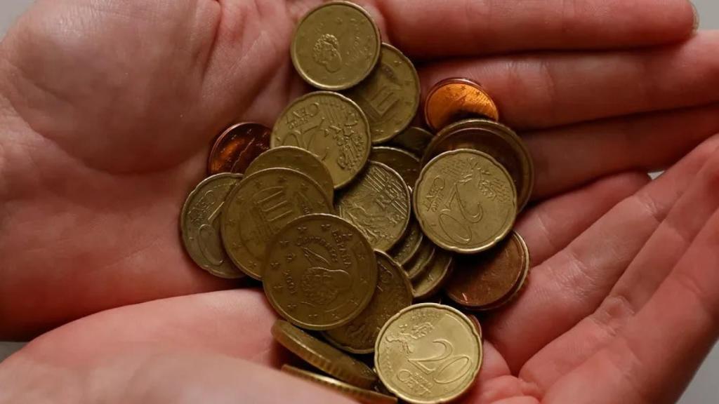 Una persona con monedas en la mano