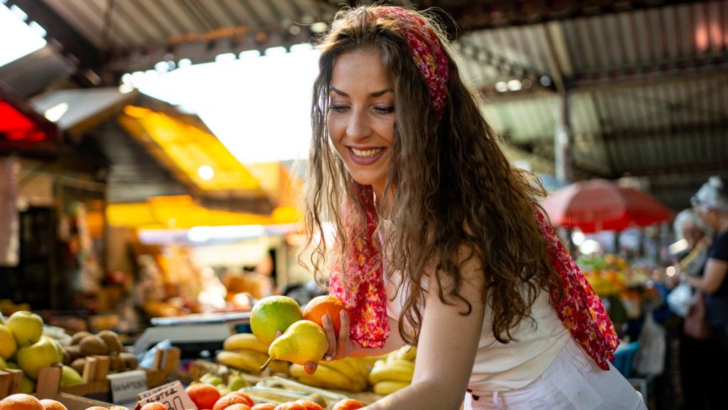 Mujer comprando frutas en el mercado.