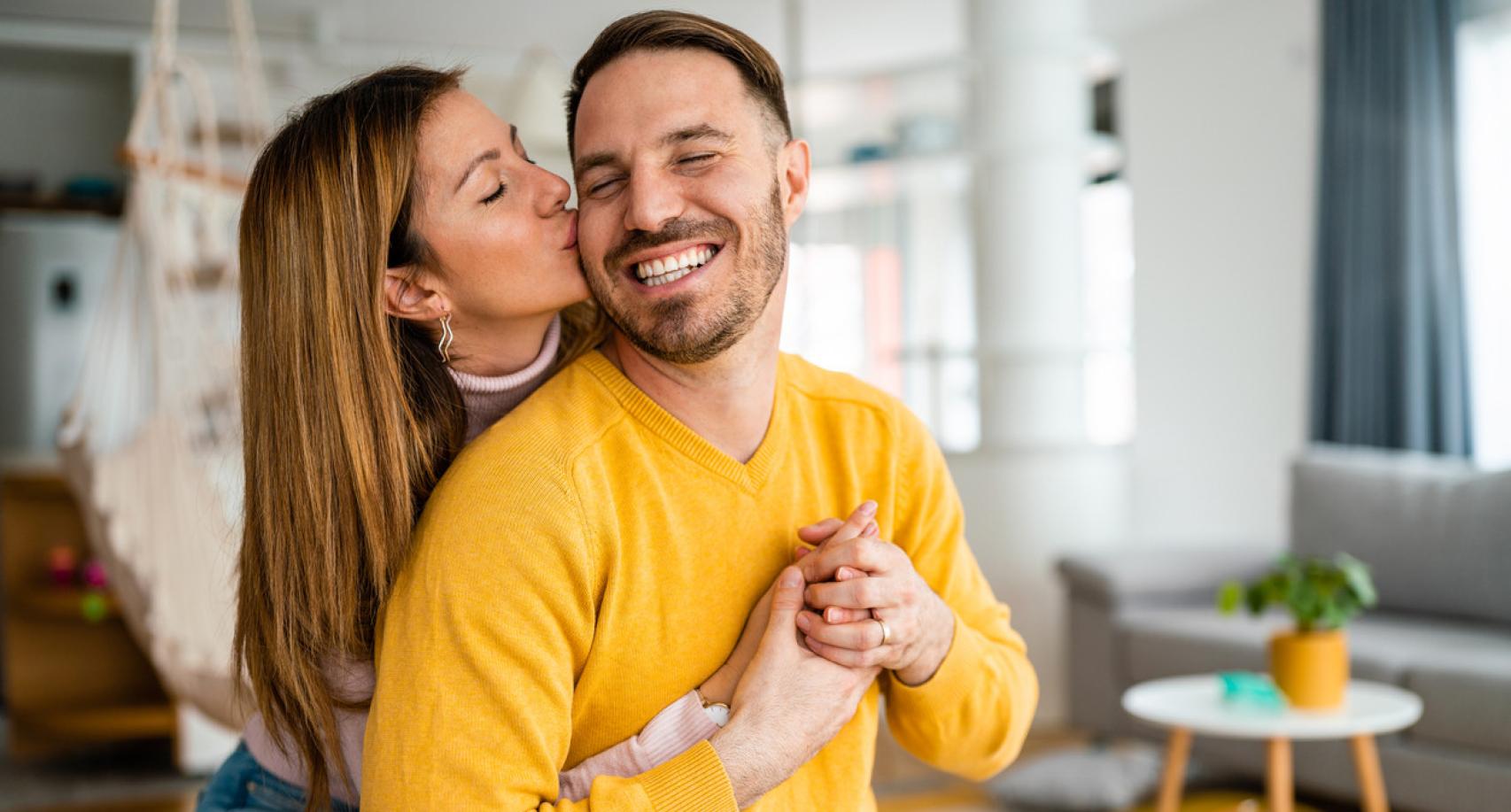 Mujer besa a su pareja mientras le abraza.