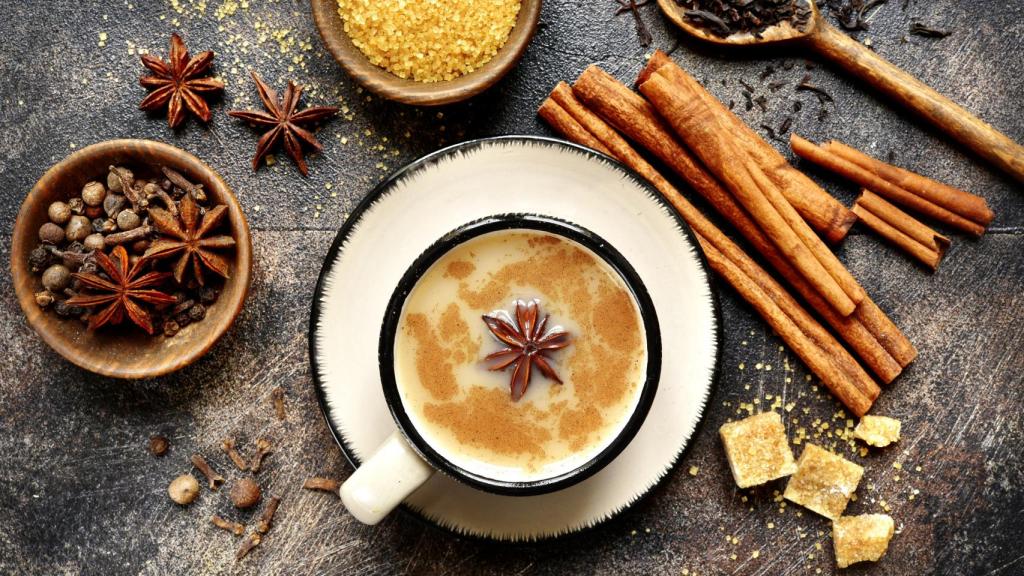 Taza de té chai junto a sus ingredientes.