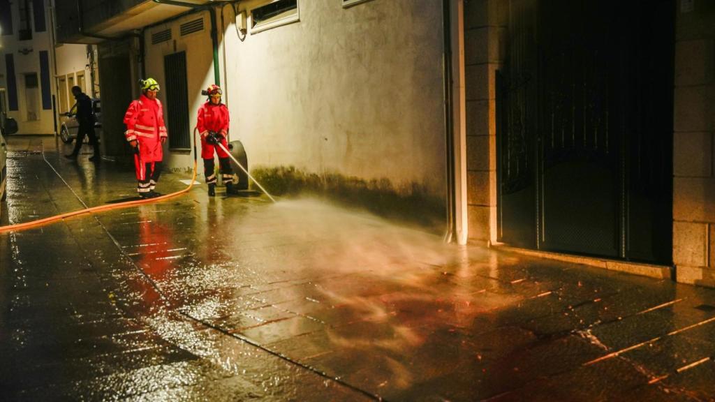 Bomberos limpian la calle de Vilaxoán de Arousa, en Vilagarcía de Arousa (Pontevedra), donde un varón asesinó supuestamente a su cuñado de una puñalada en la tarde de este viernes.