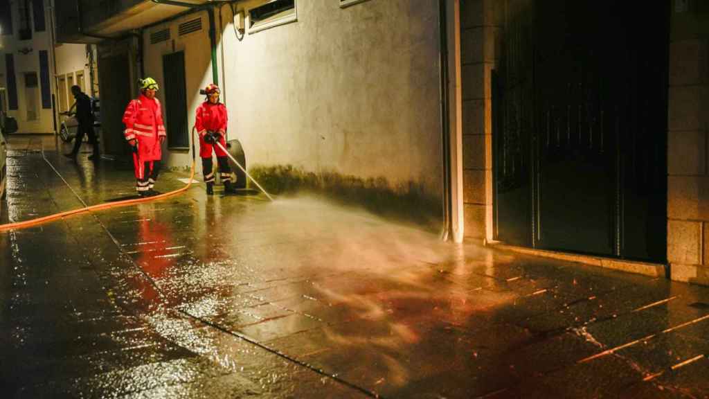 Bomberos limpian la calle de Vilaxoán de Arousa, en Vilagarcía de Arousa (Pontevedra), donde un varón asesinó supuestamente a su cuñado de una puñalada en la tarde de este viernes.