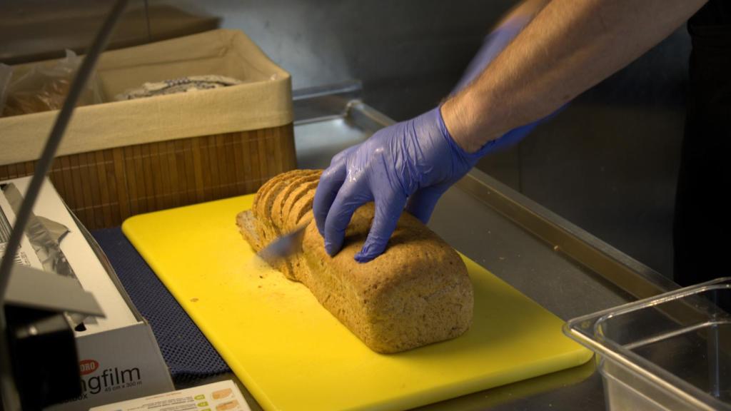 Jon corta su pan casero en la cocina.