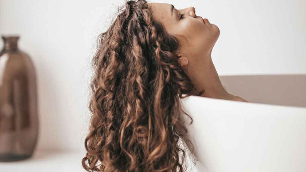 Mujer dándose un baño con el pelo por fuera de la bañera.