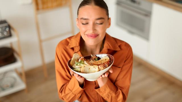 Mujer joven con un bol de comida entre las manos.