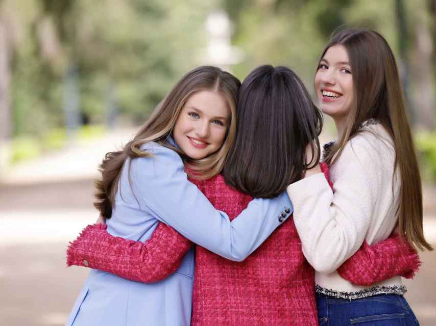Leonor y Sofía abrazan a su madre mientras sonríen a la cámara.