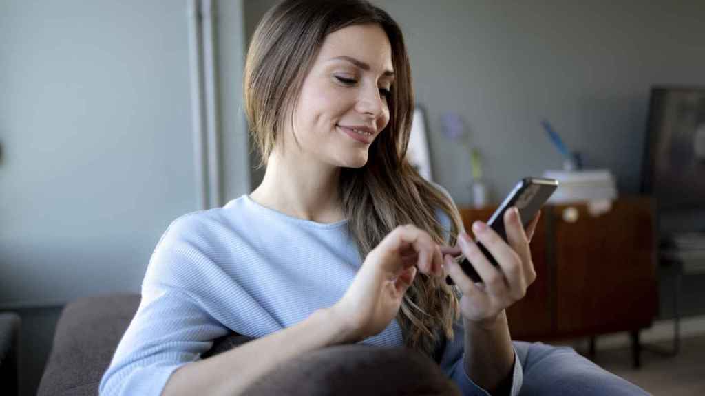 Mujer sonriente con el móvil en las manos.