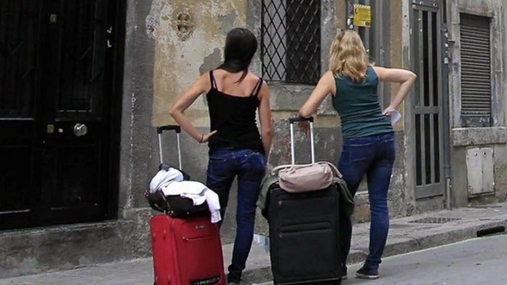 Dos personas esperando frente a un piso turístico.