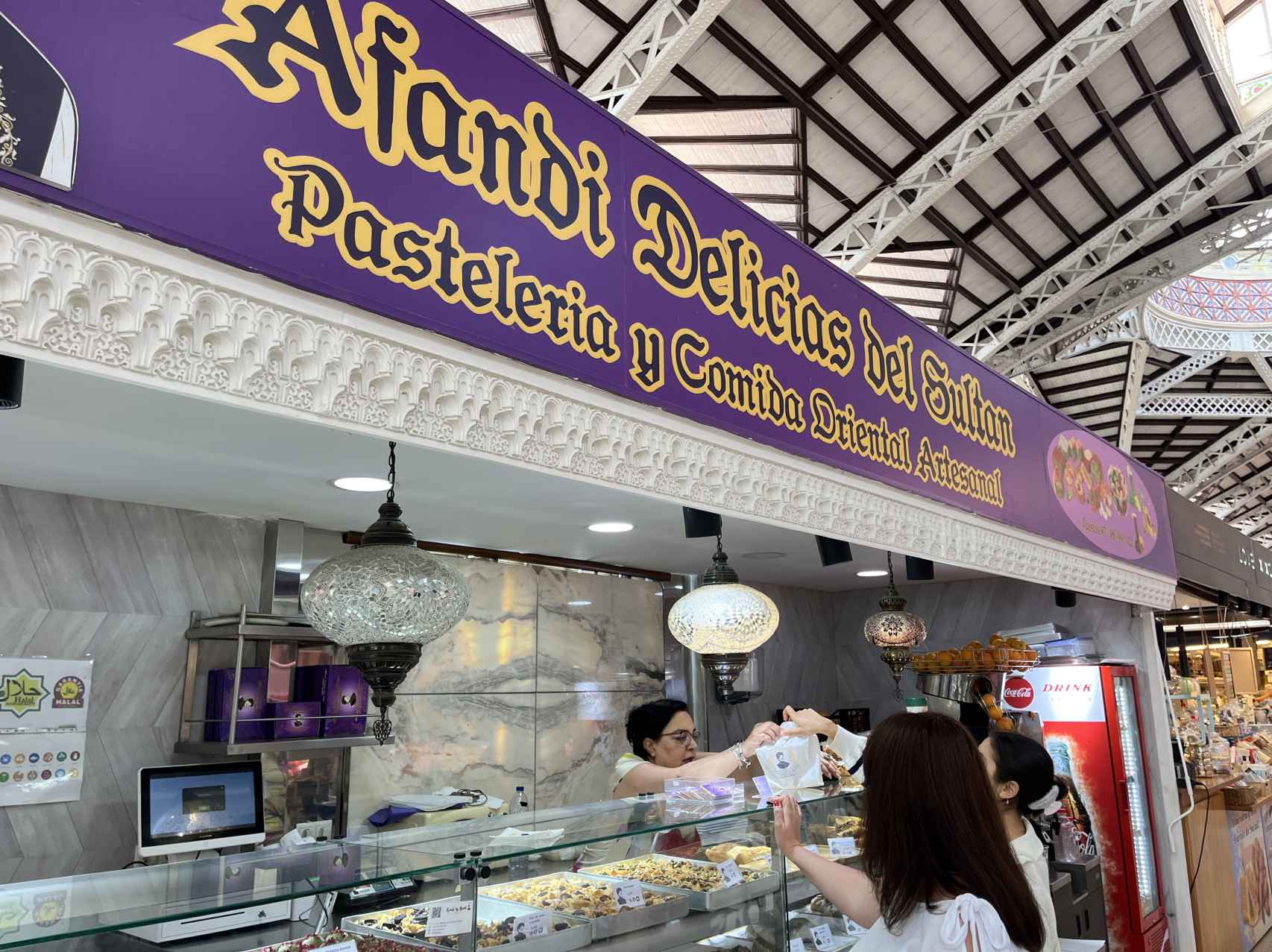 Hala Kafarnawi, mientras atiende a una clienta en su puesto en el Mercado Central de Valencia. Raquel Granell