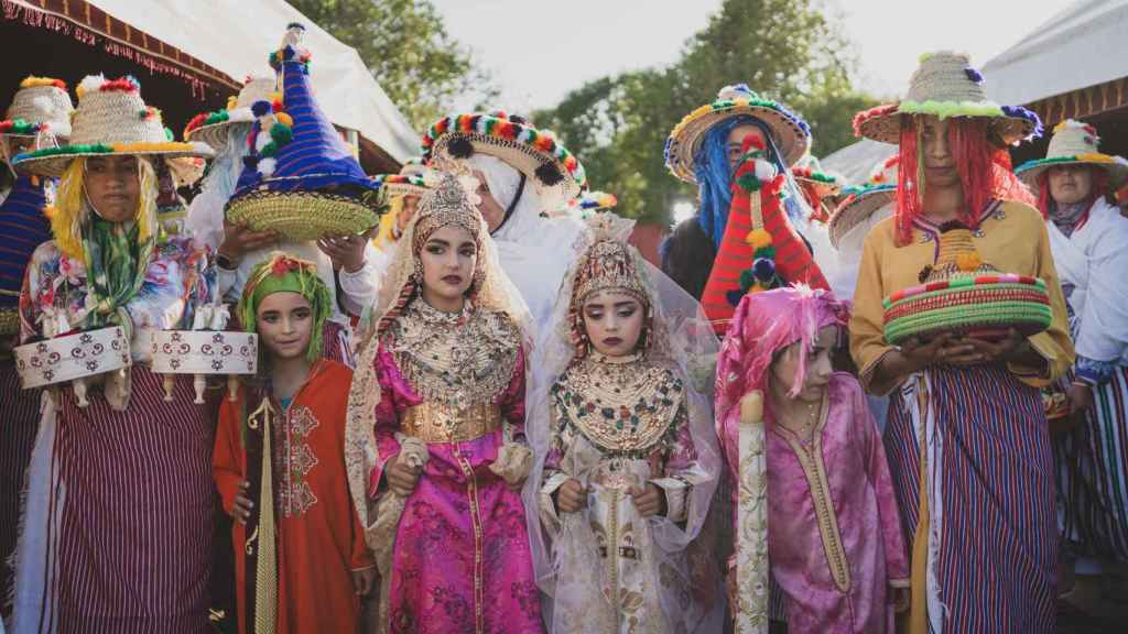 Las mujeres y un grupo de niñas presentan a la muñeca de trapo ante los participantes.