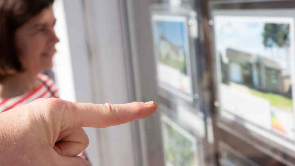 Una pareja mira el escaparate de una agencia inmobiliaria.