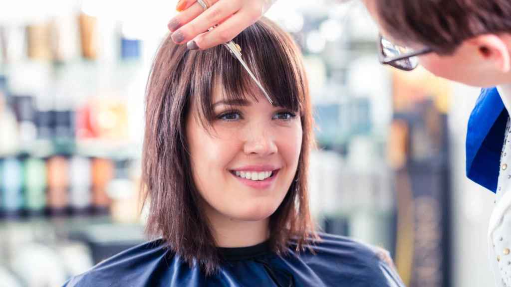 Mujer cortándose el flequillo.