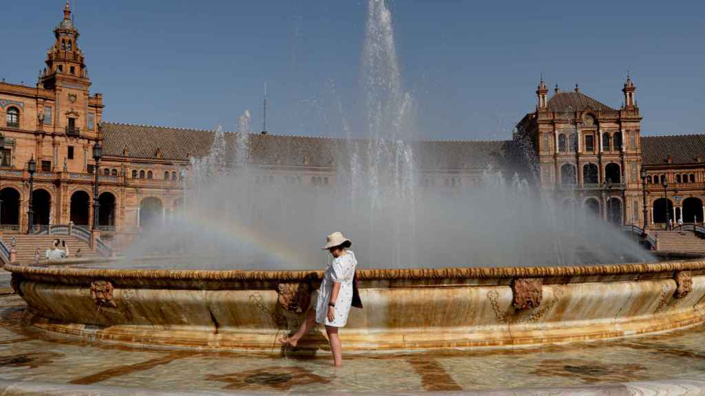 Turistas se refrescan en la fuente de la Plaza de España.