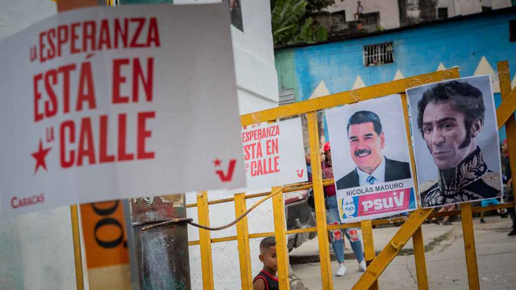 Un niño observa a través de una reja con la imagen de Maduro y de Simón Bolívar, el lunes en Caracas.