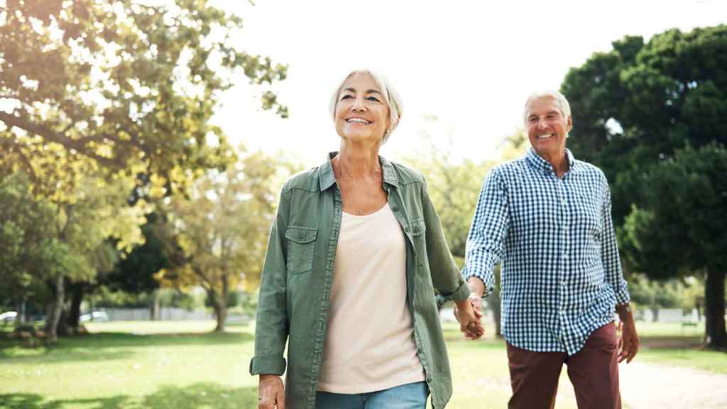 Pareja de la mano por un parque.