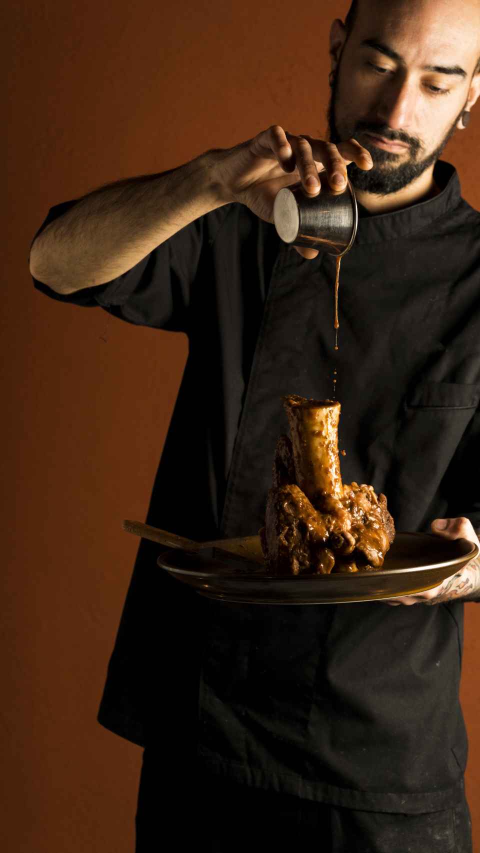 El chef Nico Martos echa el jugo en el jarrete confitado.