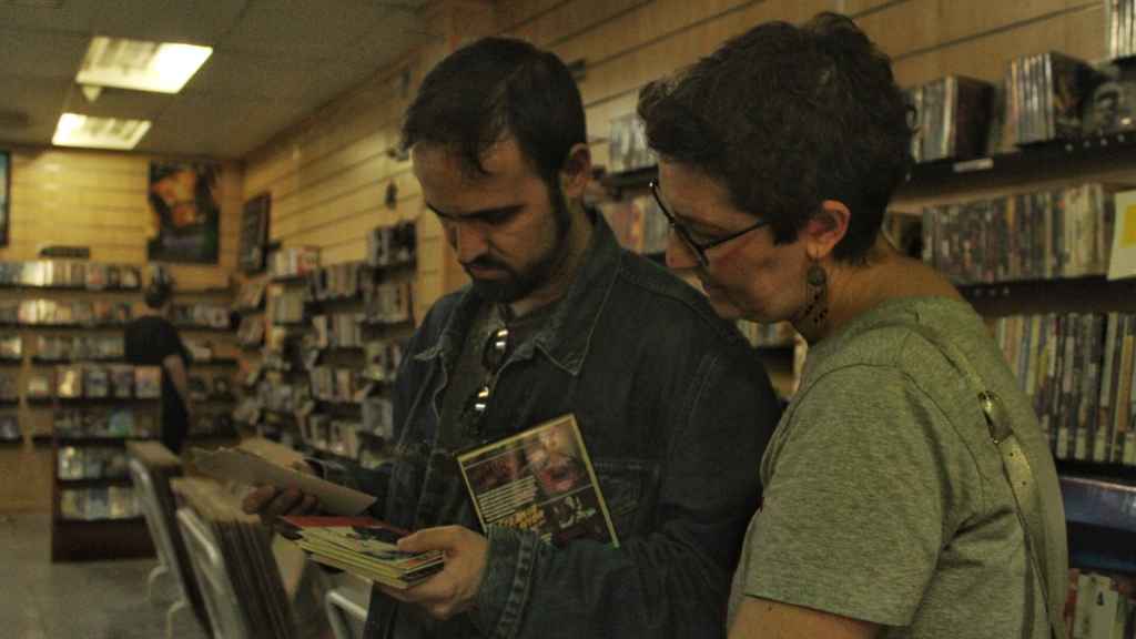 Clientes mirando las películas del videoclub Ficciones.