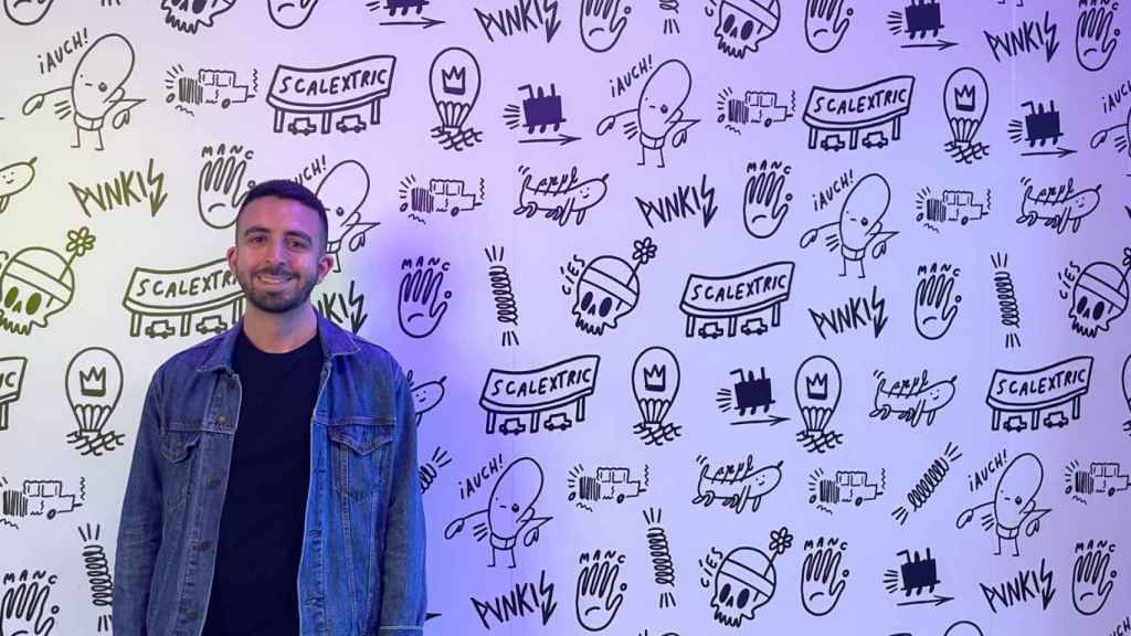 Alberto Ash Santos posando con la pared de los baños de Vialia diseñada por él.