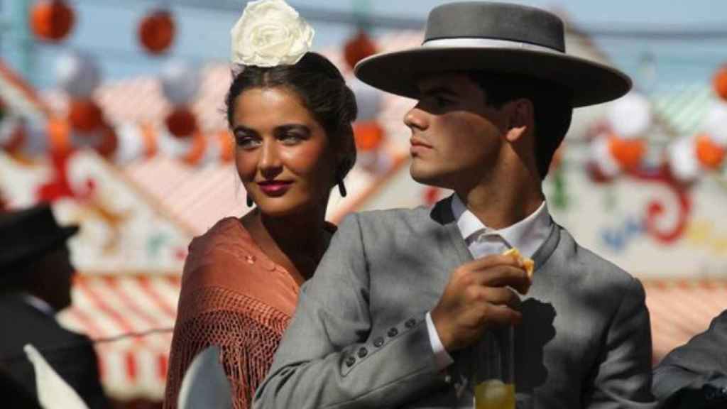 Pareja vestida con el traje típico andaluz sobre un caballo.