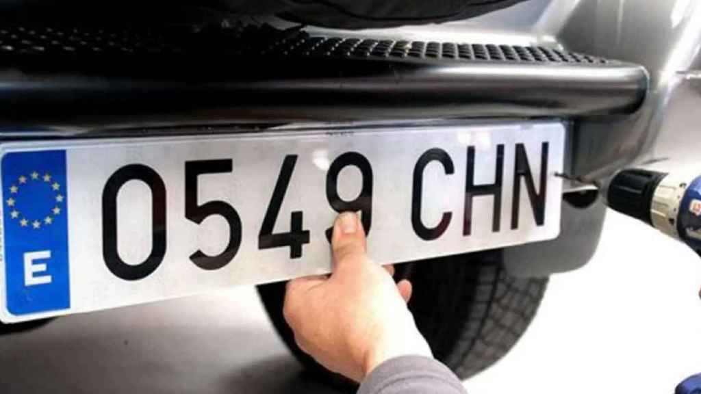 Un operario poniendo una matrícula a un coche.