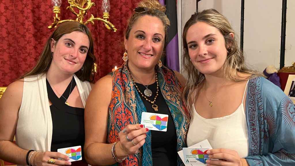 Elvira López posa junto a sus otras dos hijas con el carné de donante de órganos.