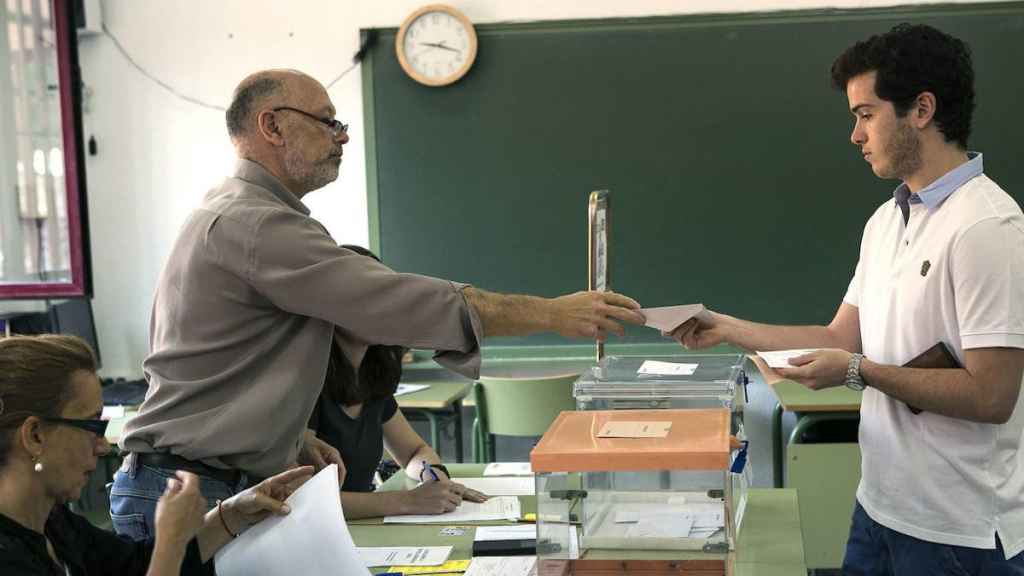 Un joven deposita su voto en la urna en un colegio electoral