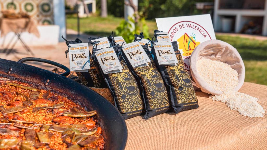 Una paella valenciana junto a diversos paquetes del arroz 'Ricepaella'.