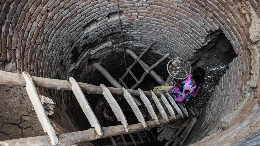 Una niña carga restos de mica en un pozo.