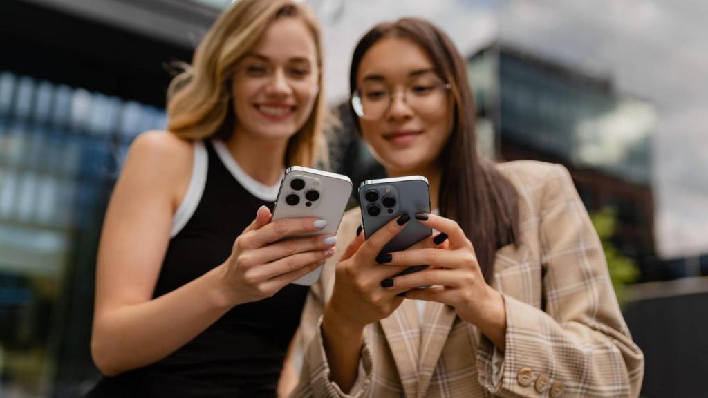 Dos jóvenes consultan su teléfono móvil