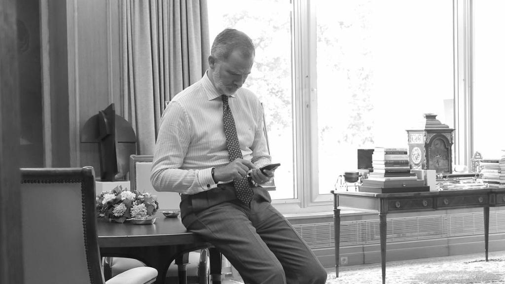 El rey Felipe VI mirando el móvil en su despacho del Palacio de la Zarzuela.