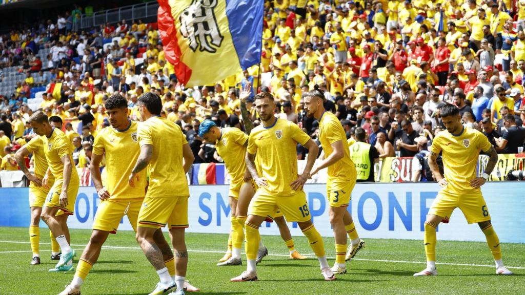 Los jugadores de Rumanía realizan ejercicios de calentamiento.