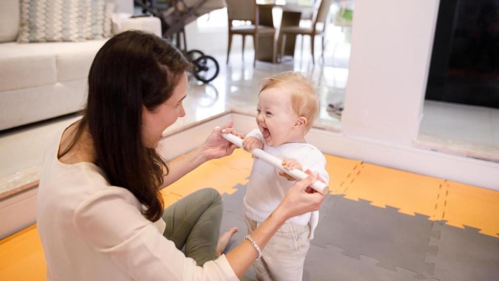 Imagen de archivo de una mujer ayudando a su bebé con discapacidad a ponerse en pie.